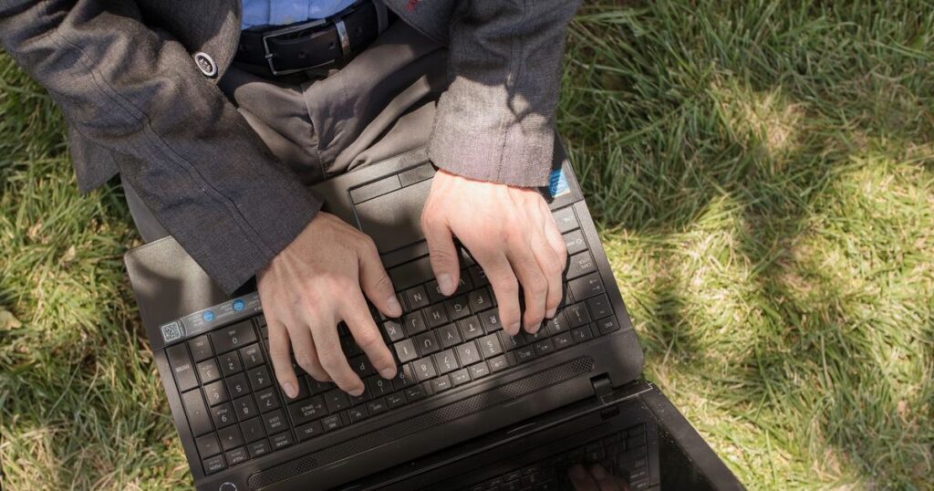 Writer adding an internal hyperlink to a blog post on a laptop